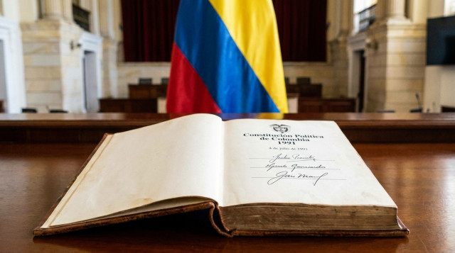 ejemplar de la Constitución Política de Colombia firmada el 4 de julio de 1991 sobre una mesa con la bandera tricolor al fondo