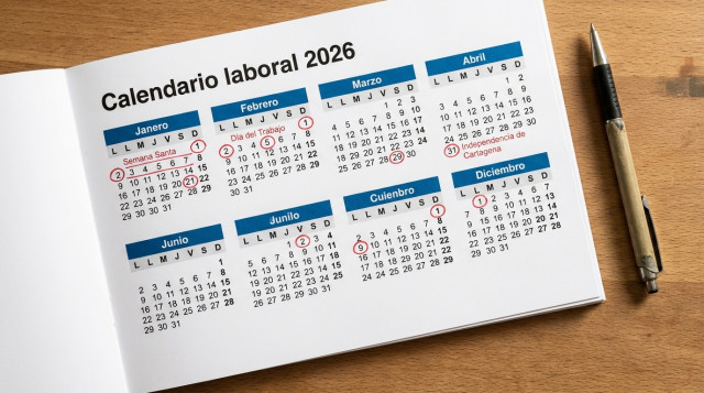 calendario impreso sobre una mesa con marcaciones rojas en los festivos de 2026 y un bolígrafo, vista cenital, con la frase «Calendario laboral 2026» visible