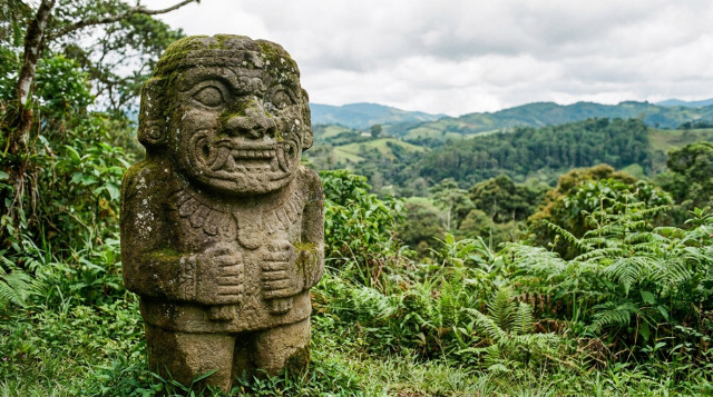 Escultura de piedra de un guardián milenario en el Parque Arqueológico de San Agustín con el paisaje verde del Huila de fondo