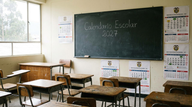 fotografía horizontal de un aula vacía con calendarios escolares colgados en la pared y un pizarrón que muestra las palabras