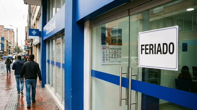 Fotografía horizontal de una sucursal bancaria cerrada con cartel de "feriado" en la puerta y calendario marcando 12 de octubre, color corporativo azul y texto alternativo que incl